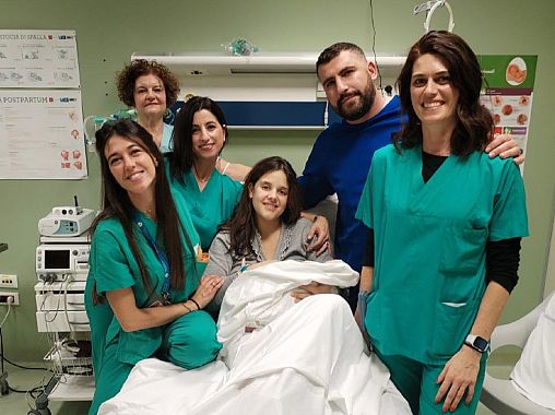 La piccola Beatrice con mamma e papà  e con lo staff sanitario che ha assistito al parto